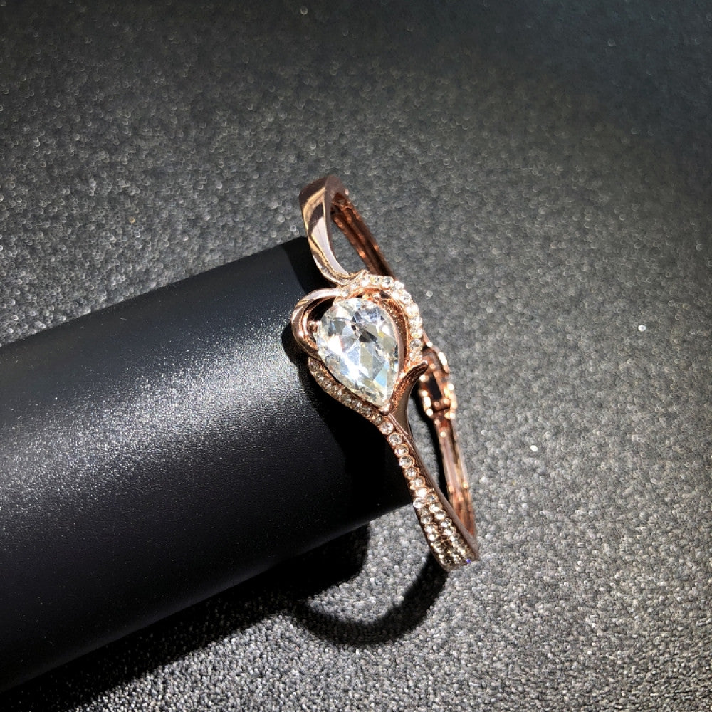 Fashion luxury rose gold bangle with diamond-encrusted signature logo, displayed on black surface, ideal for luxury fashion and statement jewelry enthusiasts 08