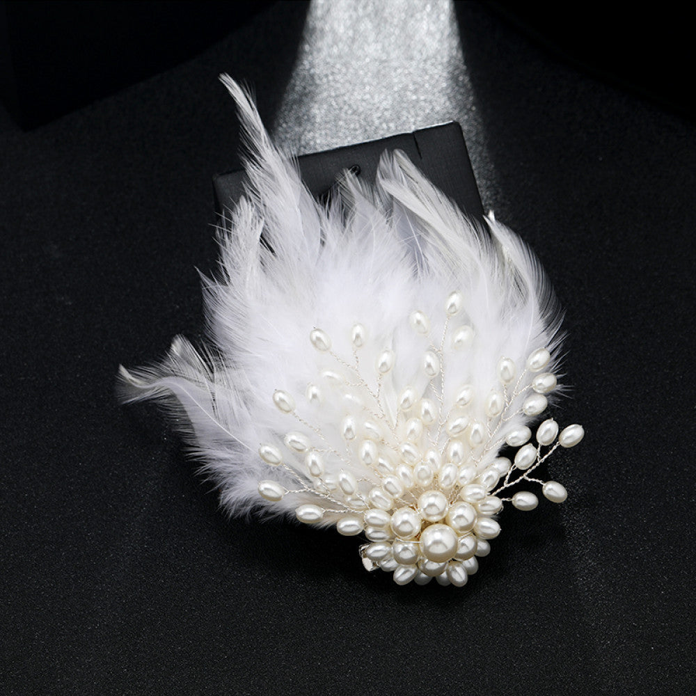 This hair accessory features light white feathers, paired with pearls and silver wire. The soft feathers and lustrous pearls create a dreamy, exquisite design, ideal for bridal looks or evening gowns.
