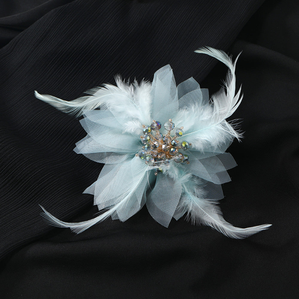 This hair accessory features light white feathers and sheer tulle, layered like a blooming flower. The center is adorned with sparkling crystals and pearls, creating a dreamy, ethereal look perfect for bridal styles or special occasions. 02