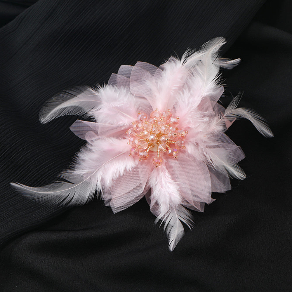 This hair accessory features light white feathers and sheer tulle, layered like a blooming flower. The center is adorned with sparkling crystals and pearls, creating a dreamy, ethereal look perfect for bridal styles or special occasions. 03