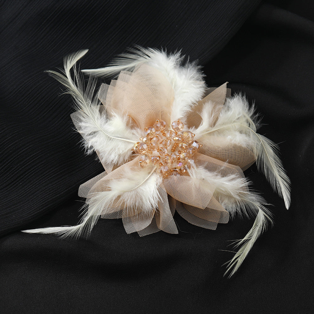 This hair accessory features light white feathers and sheer tulle, layered like a blooming flower. The center is adorned with sparkling crystals and pearls, creating a dreamy, ethereal look perfect for bridal styles or special occasions. 04