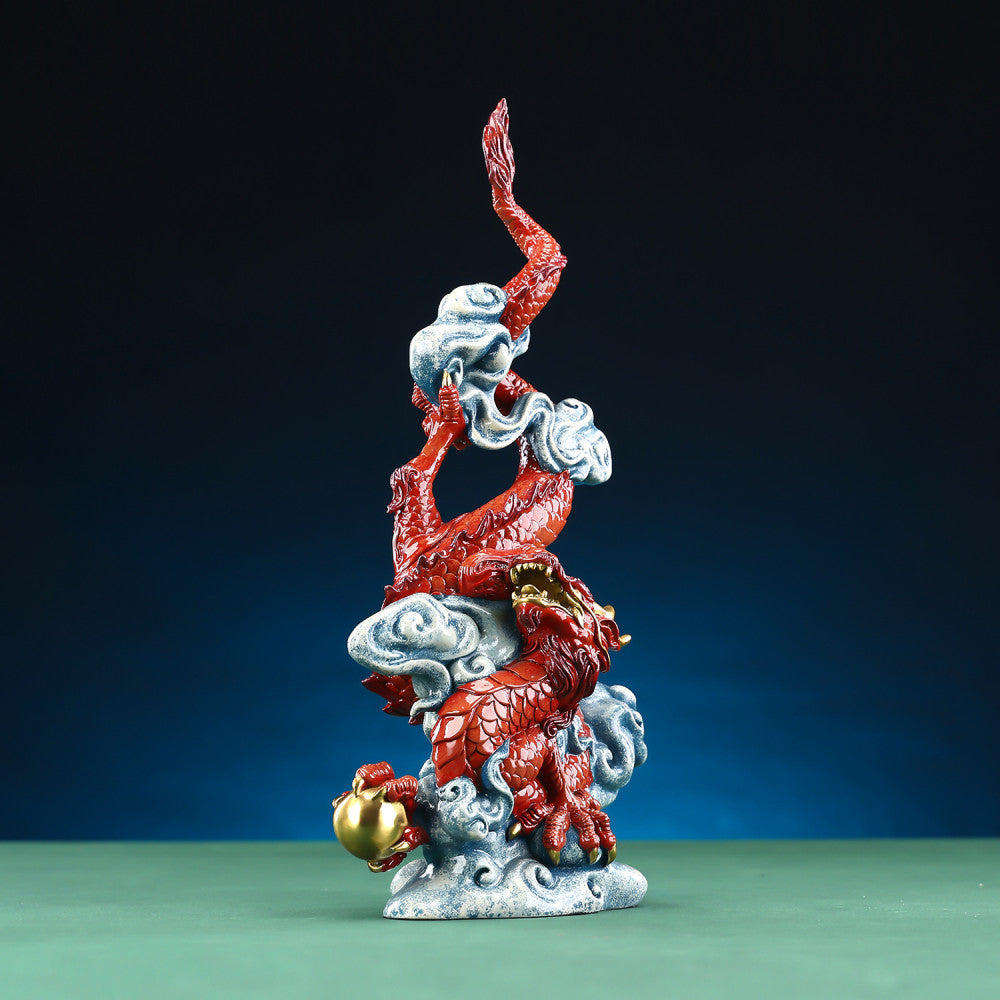 Intricate red Chinese dragon statue with gold accents, coiled around clouds and holding a treasure, a Feng Shui symbol of good luck and strength, displayed against a dark blue background