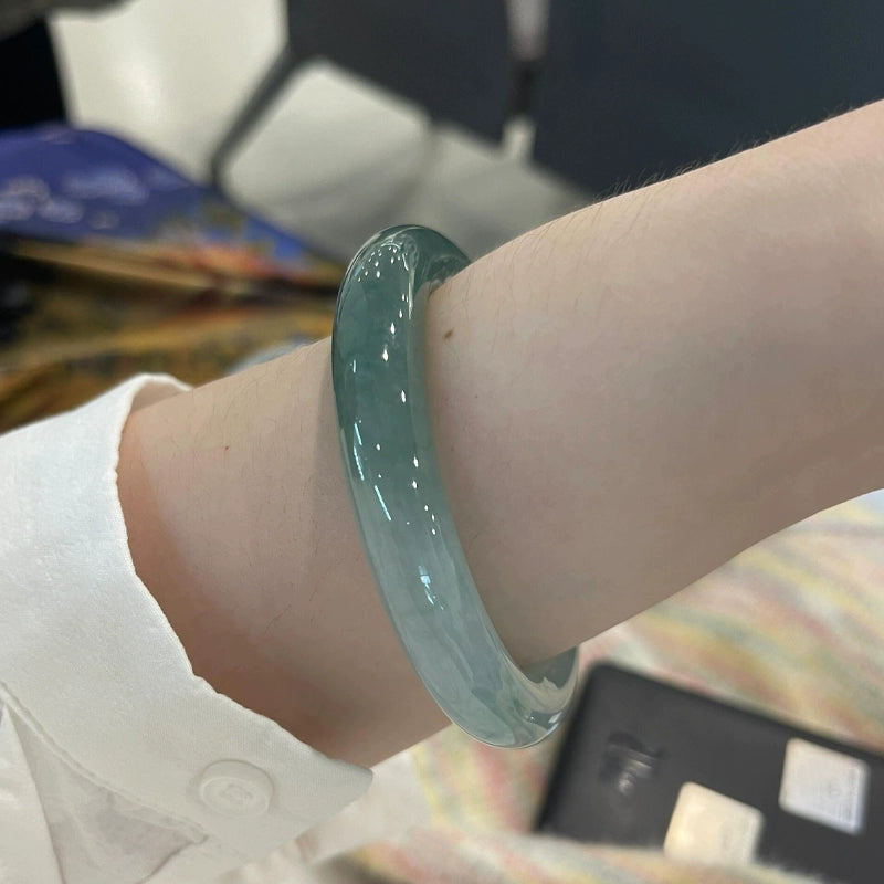 Woman wearing icy blue water natural jade bangle, translucent Chinese jade bracelet 