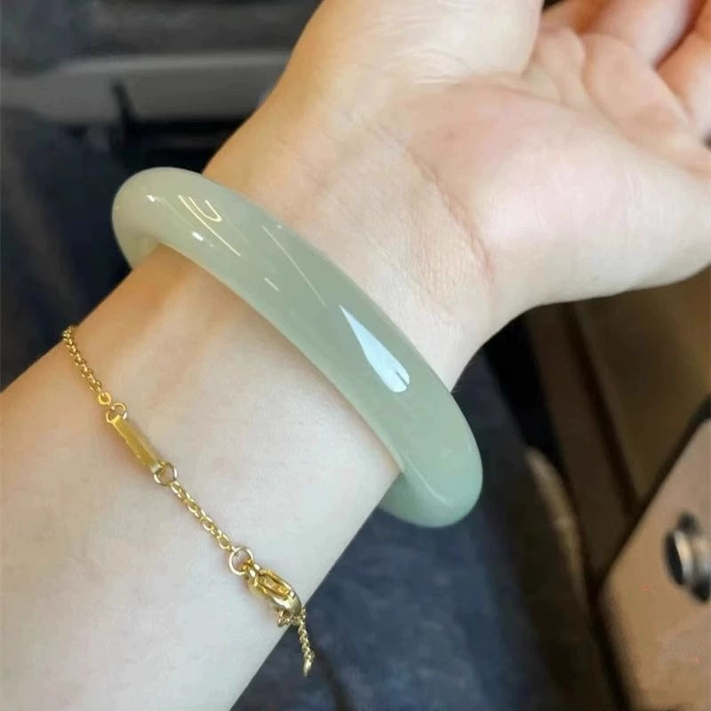Hand wearing natural light green jade bangle and red heart charm bracelet 01