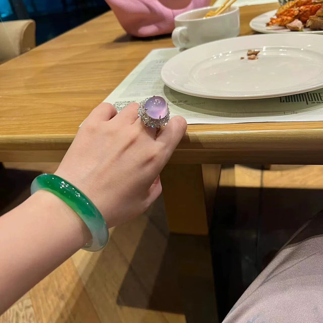 Hand wearing natural vivid green gradient jadeite bangle and lavender gem ring in elegant setting 01