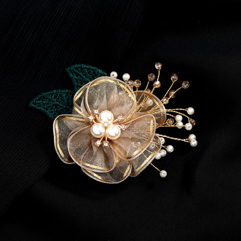 This elegant accessory features a layered navy tulle flower at its center, adorned with lustrous pearls and sparkling crystals. Delicate gold wire sprigs dotted with white and blue beads extend outward, complemented by a rich green lace leaf. Perfect for adding a touch of sophistication to evening gowns, blazers, or special occasion outfits, this piece blends delicate craftsmanship with timeless elegance. 04