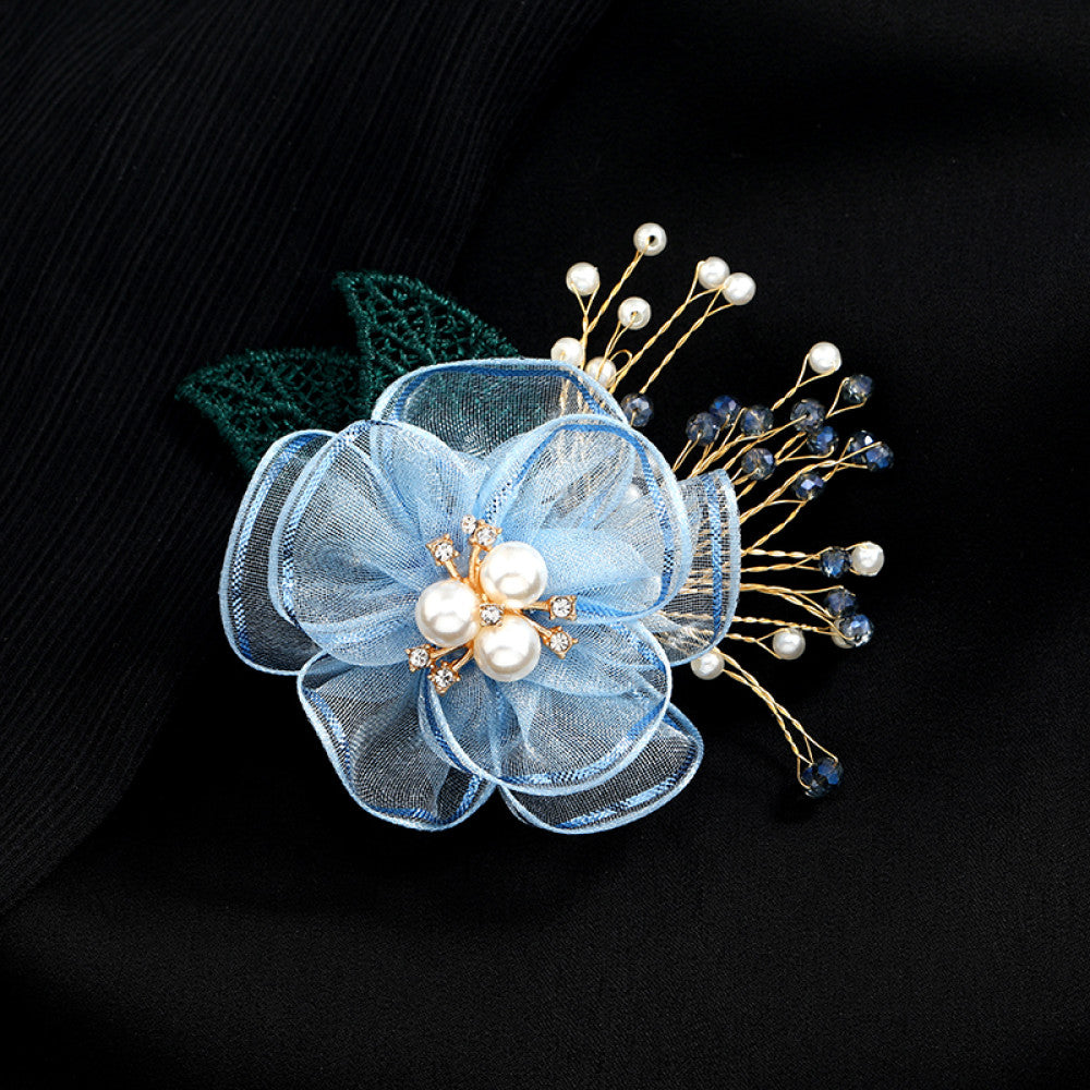 This elegant accessory features a layered navy tulle flower at its center, adorned with lustrous pearls and sparkling crystals. Delicate gold wire sprigs dotted with white and blue beads extend outward, complemented by a rich green lace leaf. Perfect for adding a touch of sophistication to evening gowns, blazers, or special occasion outfits, this piece blends delicate craftsmanship with timeless elegance. 03