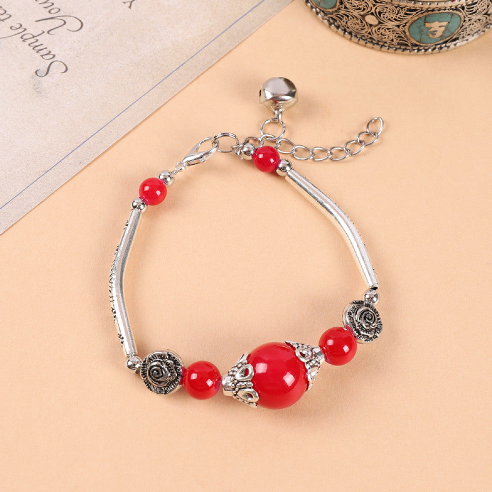 Red beads with round silver tag, symbolizing good fortune.
