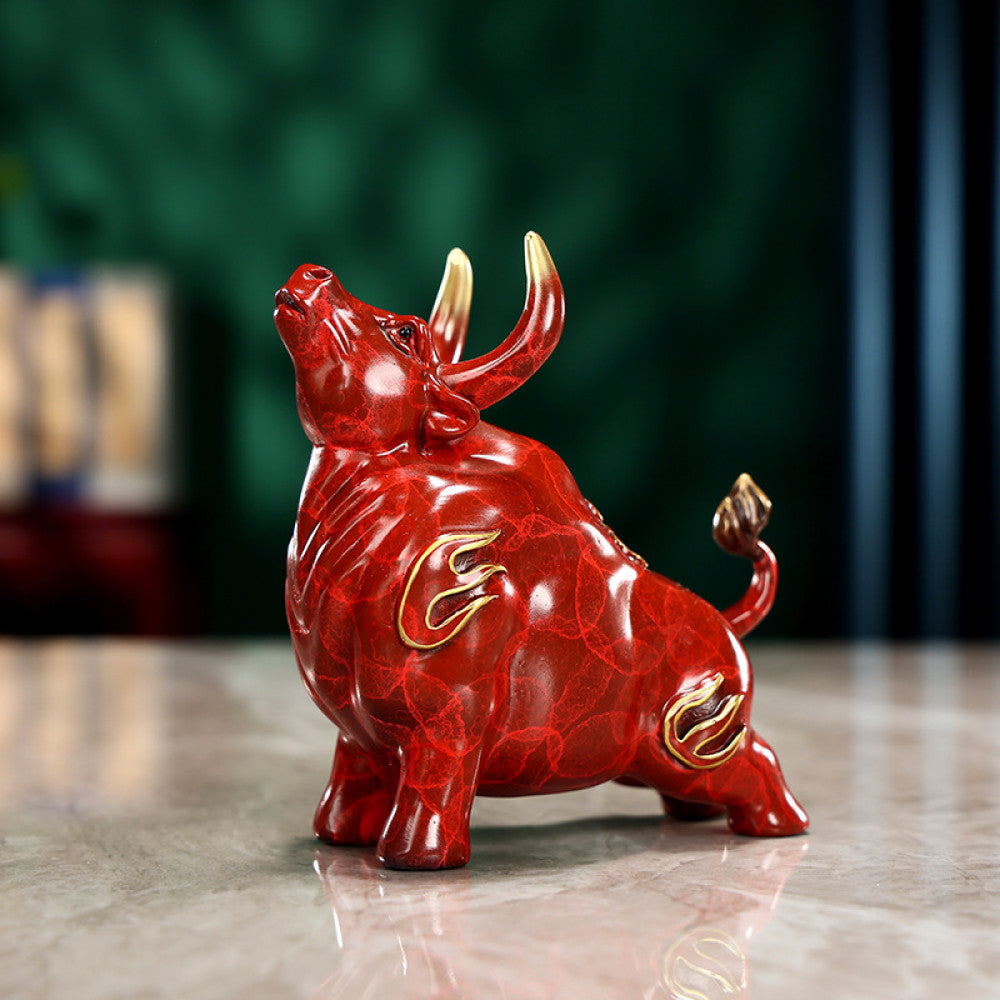 Red bull statue with golden accents and intricate details, a Feng Shui symbol of strength and good fortune, displayed on a polished surface against a green background