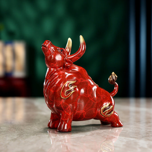 Red bull statue with golden accents and intricate details, a Feng Shui symbol of strength and good fortune, displayed on a polished surface against a green background