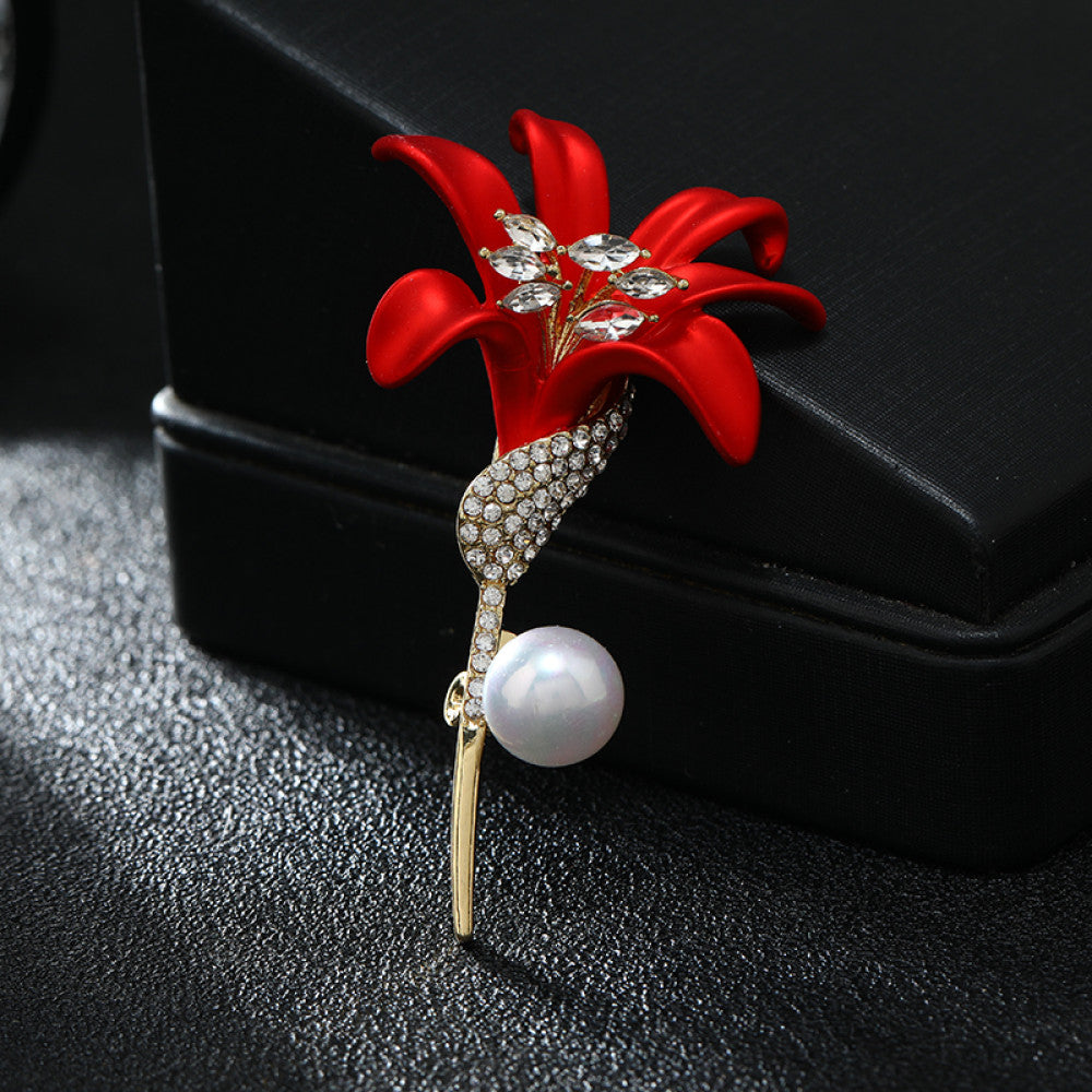This elegant brooch features a vibrant red lily with a crystal-encrusted gold stem, accented by a lustrous pearl. A sophisticated floral accessory for any outfit 01