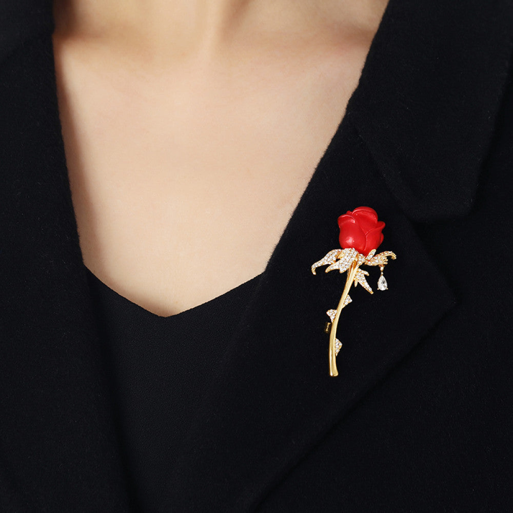 This elegant brooch features a vivid red rose with a gold crystal-encrusted stem, accented by a delicate teardrop detail. A romantic accessory to elevate any outfit 02