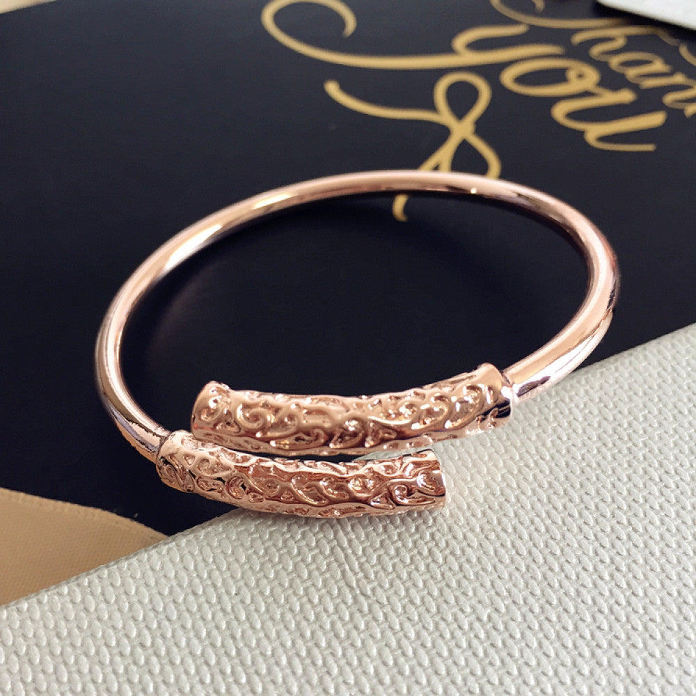 Rose gold plated bangle with engraved detail, displayed on textured surface, ideal for luxury fashion and minimalist jewelry enthusiasts