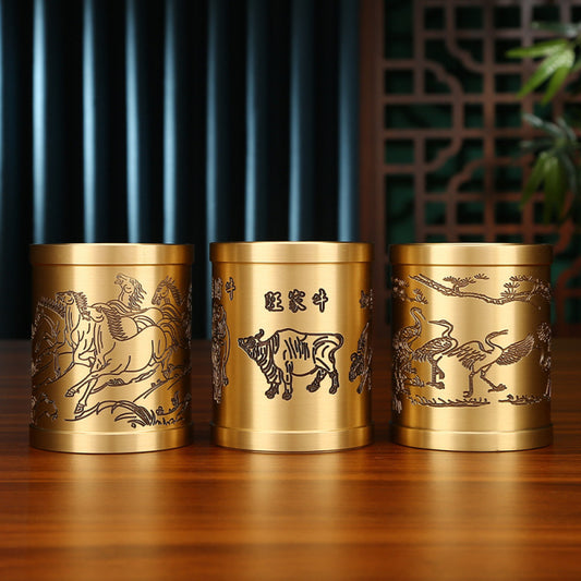 Three traditional Chinese brass pen holders with zodiac animal and Chinese character carvings, placed on a wooden table against a traditional interior background