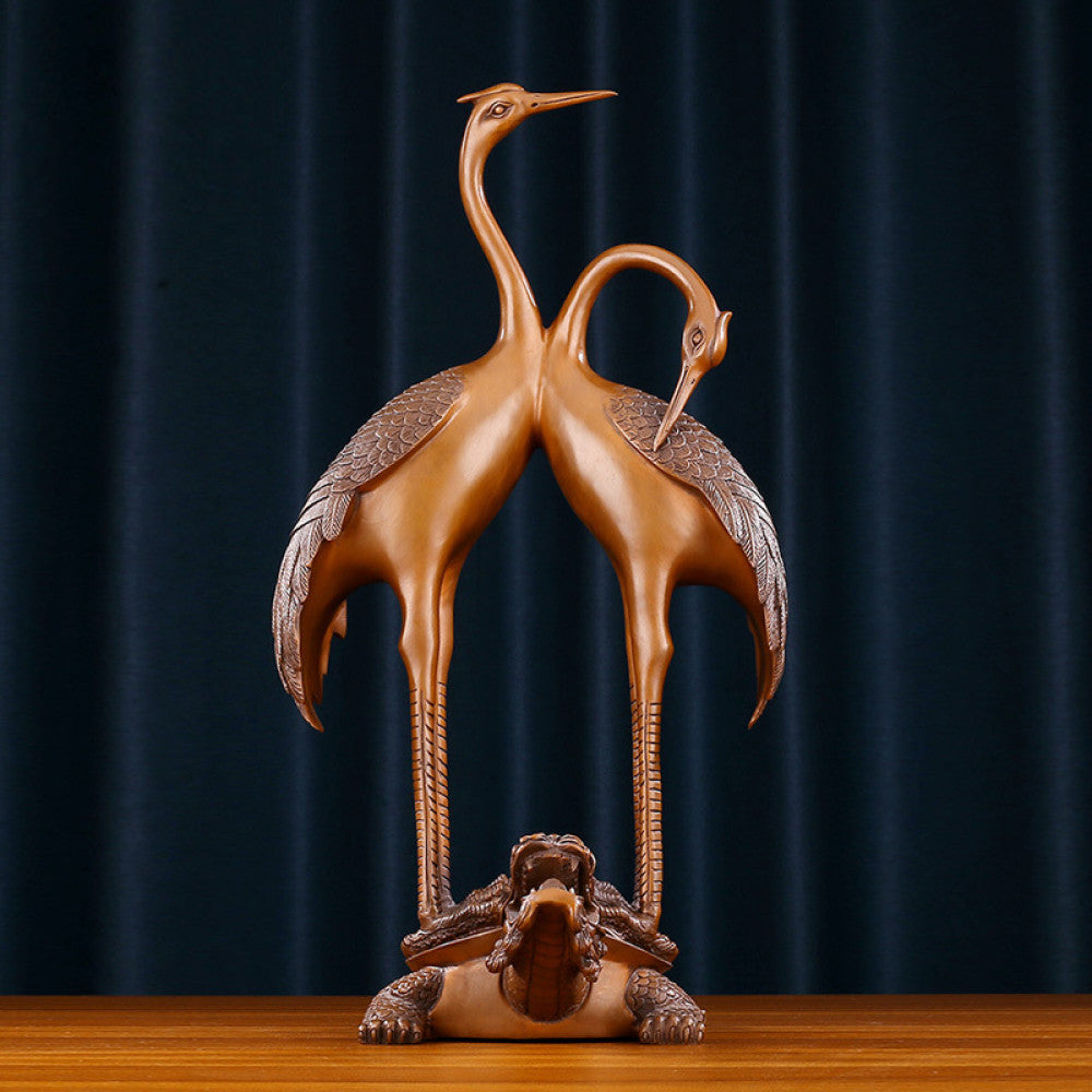 Traditional Chinese bronze crane pair statue with intertwined necks, standing on a dragon turtle base against a dark blue curtain background