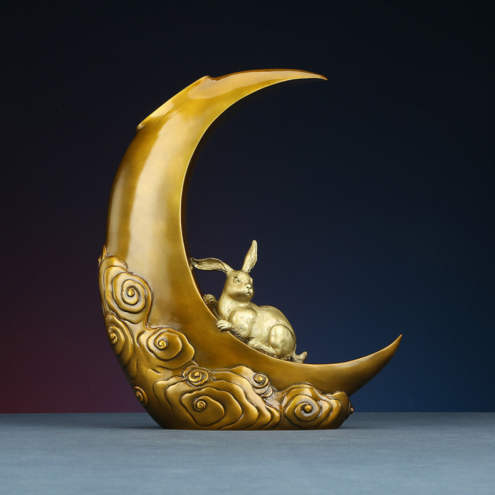 Traditional Chinese bronze sculpture of a crescent moon with a rabbit and cloud patterns, placed against a dark gradient background