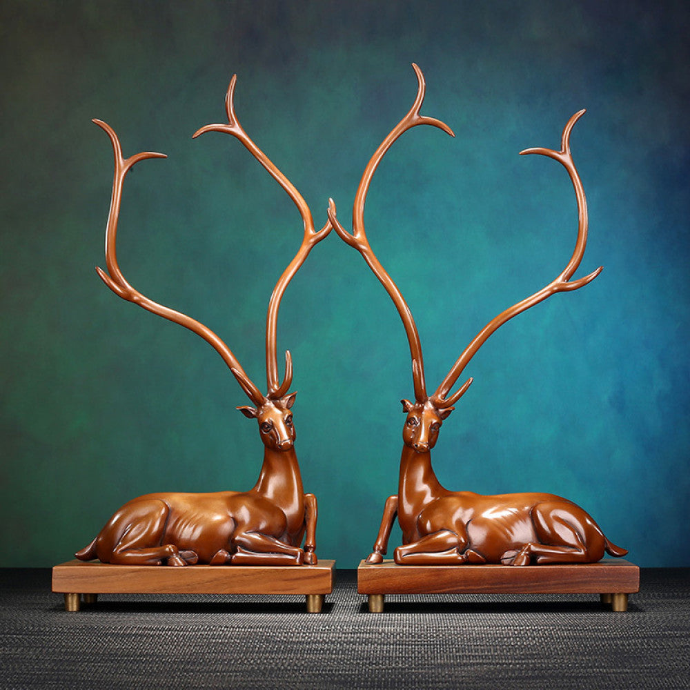 Pair of traditional Chinese bronze deer statues with large antlers, lying on wooden bases against a teal gradient background