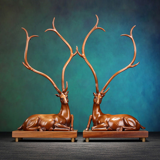 Pair of traditional Chinese bronze deer statues with large antlers, lying on wooden bases against a teal gradient background