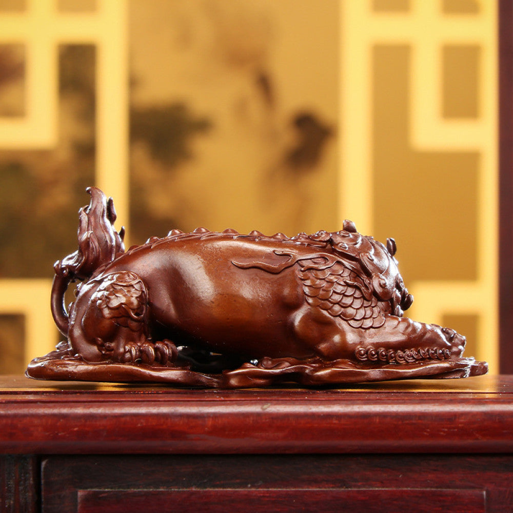Traditional Chinese bronze mythical beast statue with intricate carvings, placed on a wooden surface against an ornate golden background