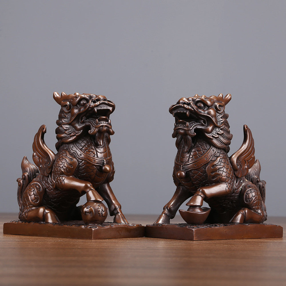 Pair of traditional Chinese bronze Qilin statues, one with a ball and one with a yuanbao ingot, placed on wooden bases against a gray background
