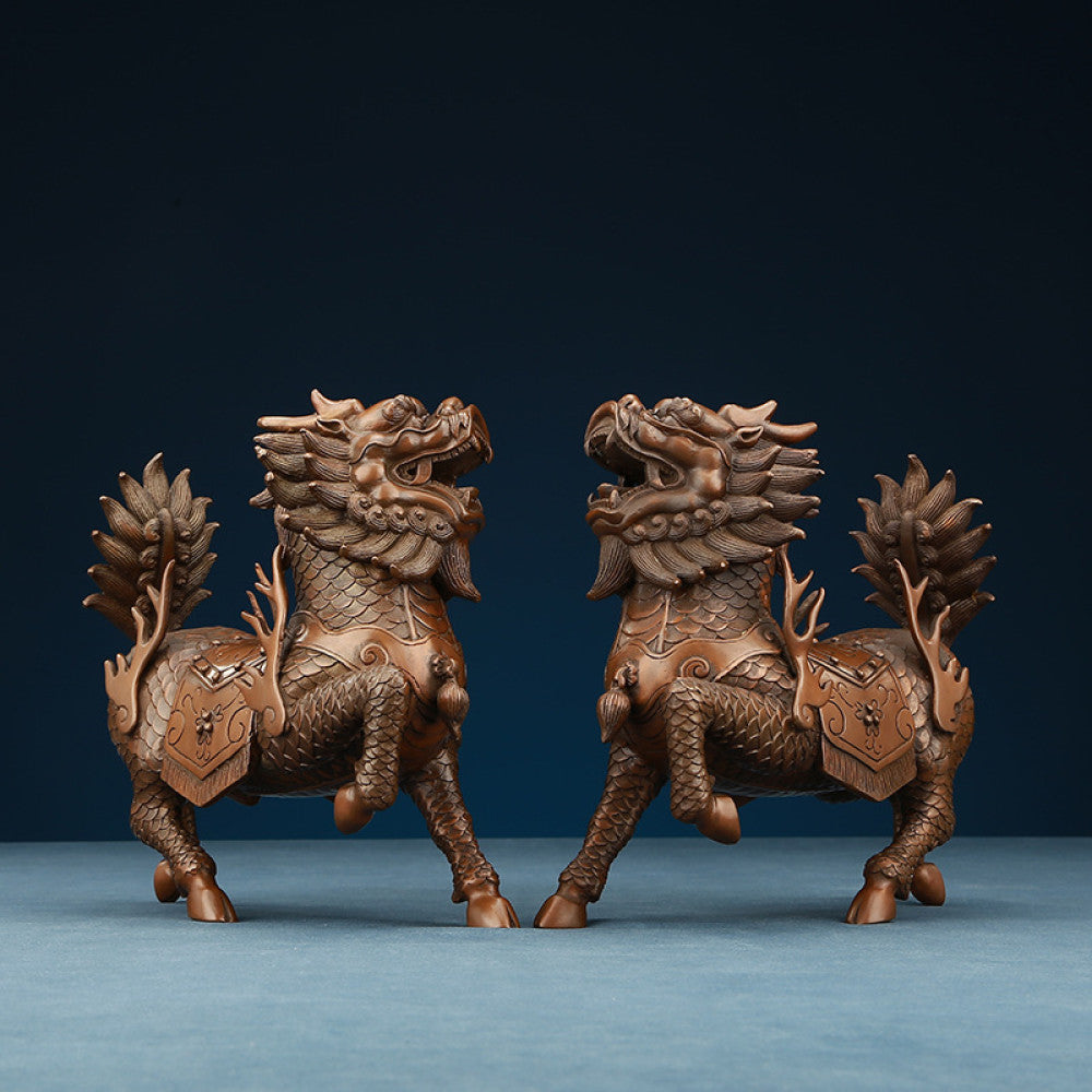 Pair of traditional Chinese bronze Qilin statues with intricate details, facing each other against a dark blue background 
