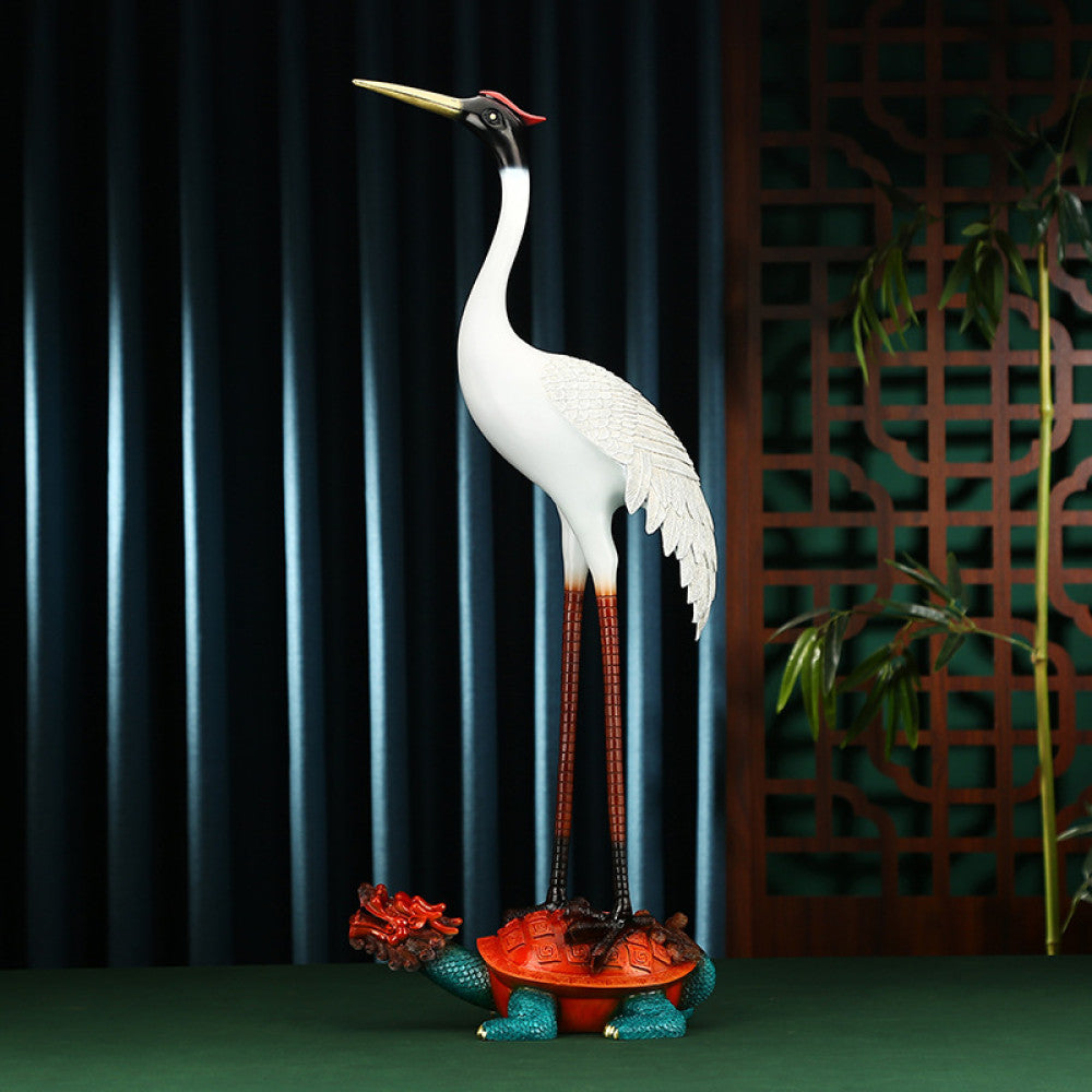 Traditional Chinese crane statue standing on a colorful tortoise, positioned against a dark screen with Chinese lattice pattern and bamboo in the background