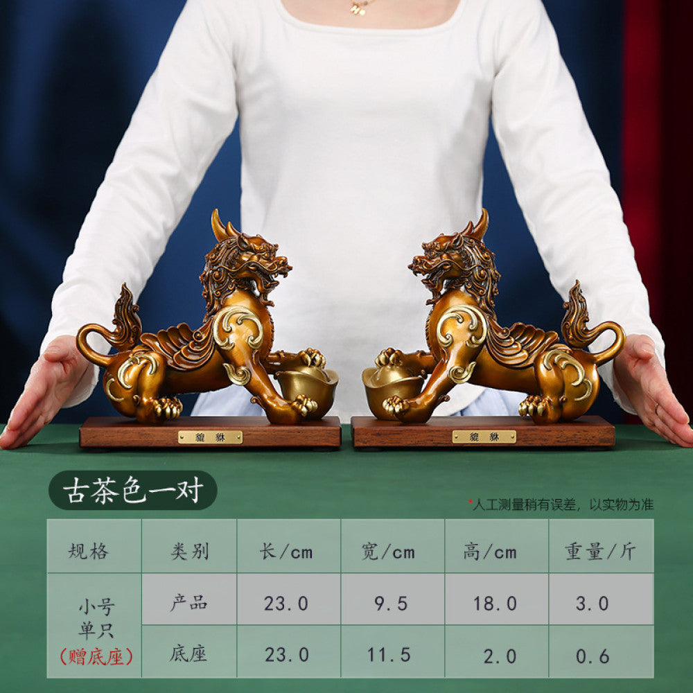 Pair of traditional Chinese Pi Xiu statues with gold inlay, holding gold ingots, placed on wooden bases against a red background