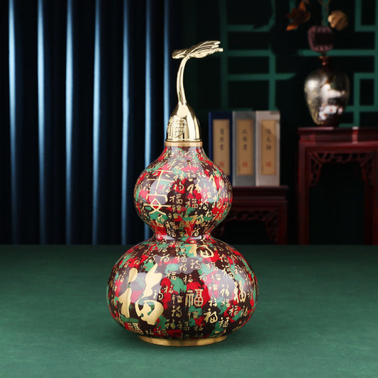 Colorful enameled Chinese gourd  decoration with golden accents, placed on green surface in traditional interior setting