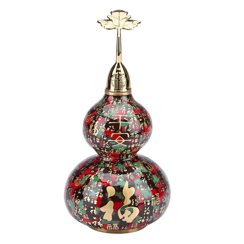 Colorful enameled Chinese gourd  decoration with golden accents, placed on green surface in traditional interior setting