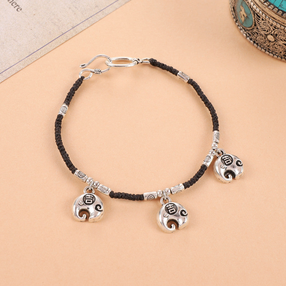 Black woven cord with three silver bell charms, vintage tribal vibe.