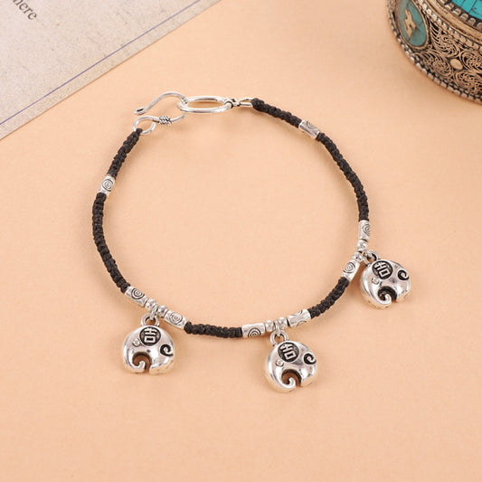 Black woven cord with three silver bell charms, vintage tribal vibe.