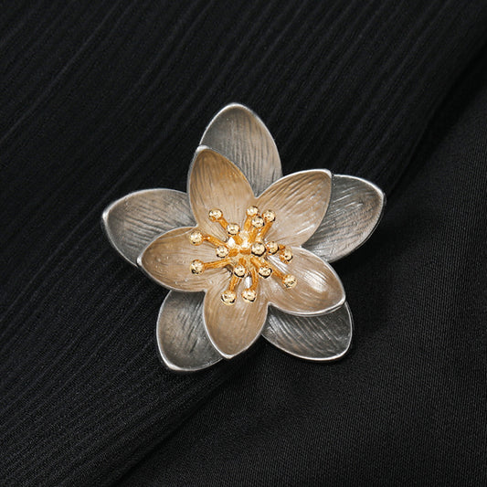 This elegant floral brooch features a striking two-tone metal design, with silver-toned outer petals and warm gold inner petals showcasing a delicate, brushed texture. The center is adorned with a cluster of sparkling clear crystals, adding a touch of luminous sophistication. Perfect for elevating blazers, scarves, or everyday outfits, this piece blends modern design with timeless floral charm.
