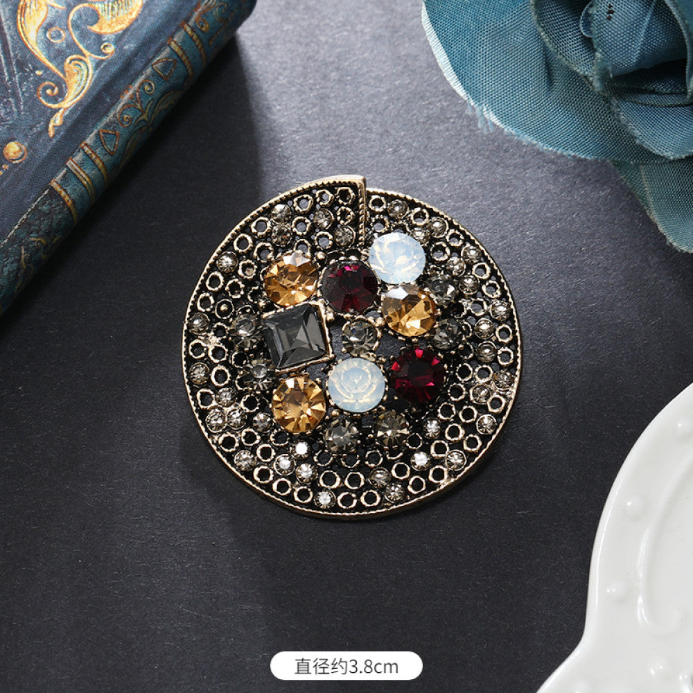 This vintage brooch set features an antiqued bronze base, adorned with pearls, colored crystals, and gemstones. The circular design sparkles with dense small crystals; the arrow-shaped piece carries a tribal vibe with a pearl pendant; the large gemstone brooch boasts a bold black stone with surrounding pearls and gems. Ideal for elevating the sophistication and vintage charm of your coats, blazers, or dresses. 01