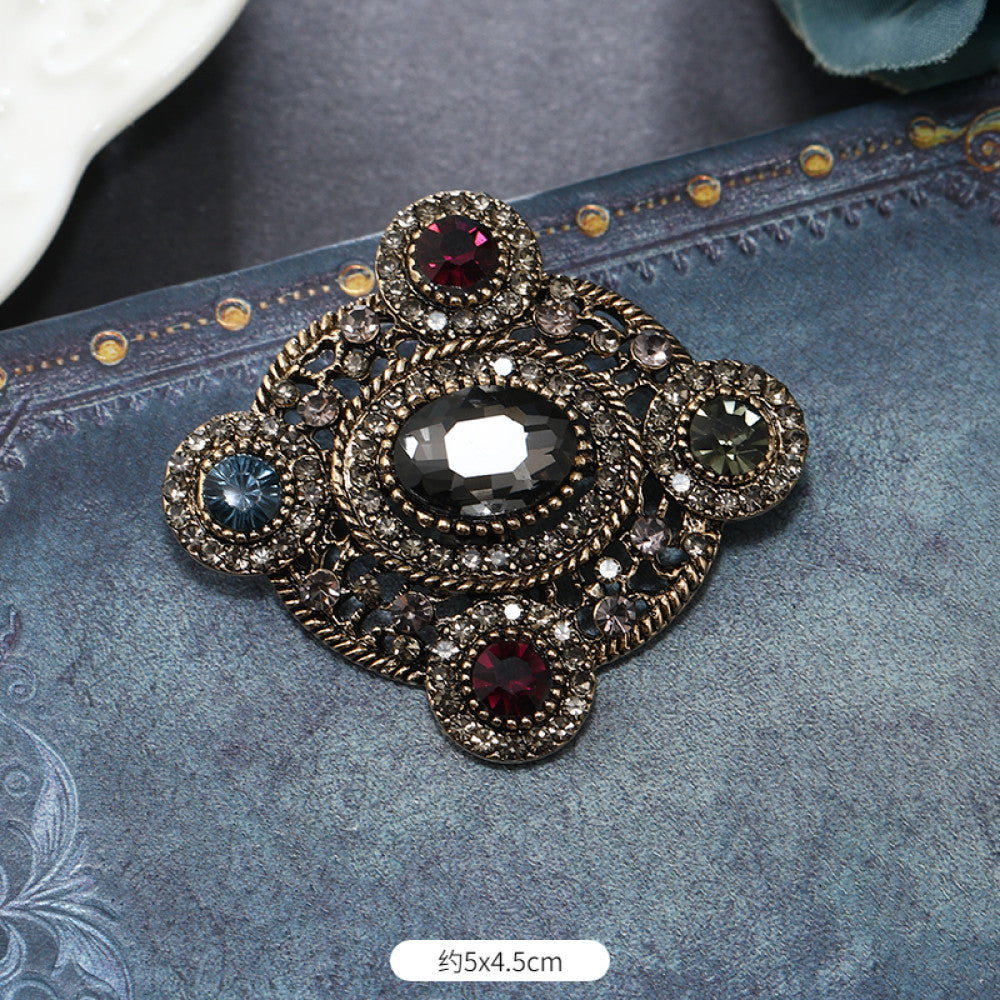 This vintage brooch set features an antiqued bronze base, adorned with pearls, colored crystals, and gemstones. The circular design sparkles with dense small crystals; the arrow-shaped piece carries a tribal vibe with a pearl pendant; the large gemstone brooch boasts a bold black stone with surrounding pearls and gems. Ideal for elevating the sophistication and vintage charm of your coats, blazers, or dresses. 02