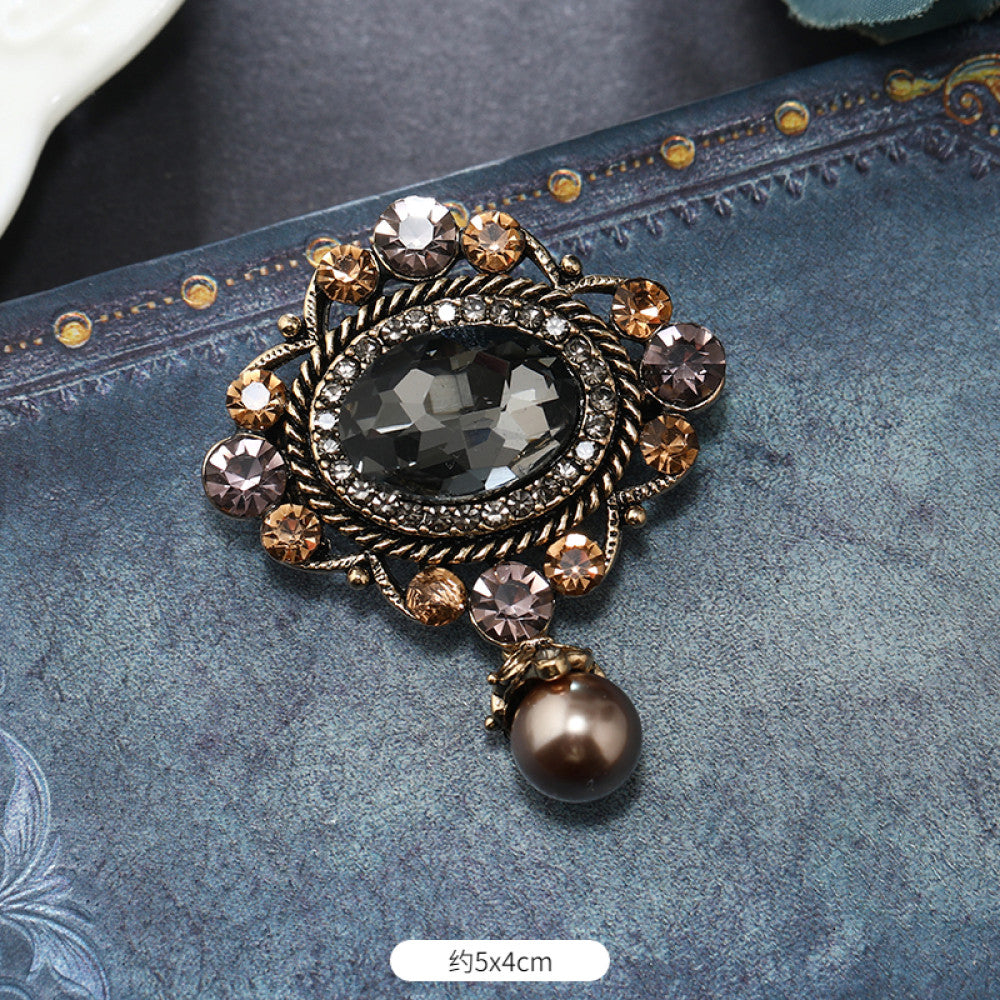 This vintage brooch set features an antiqued bronze base, adorned with pearls, colored crystals, and gemstones. The circular design sparkles with dense small crystals; the arrow-shaped piece carries a tribal vibe with a pearl pendant; the large gemstone brooch boasts a bold black stone with surrounding pearls and gems. Ideal for elevating the sophistication and vintage charm of your coats, blazers, or dresses. 03