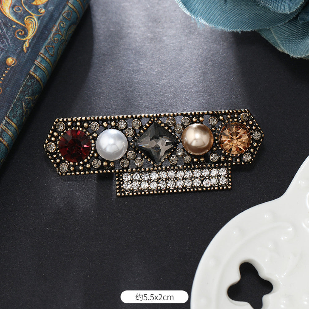 This vintage brooch set features an antiqued bronze base, adorned with pearls, colored crystals, and gemstones. The circular design sparkles with dense small crystals; the arrow-shaped piece carries a tribal vibe with a pearl pendant; the large gemstone brooch boasts a bold black stone with surrounding pearls and gems. Ideal for elevating the sophistication and vintage charm of your coats, blazers, or dresses. 07