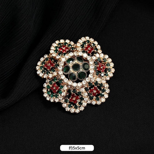 This ornate multi-layer floral brooch features vibrant red and green gemstones set in a clear crystal frame, adding a touch of vintage glamour to any outfit. Measures approx. 5x5cm