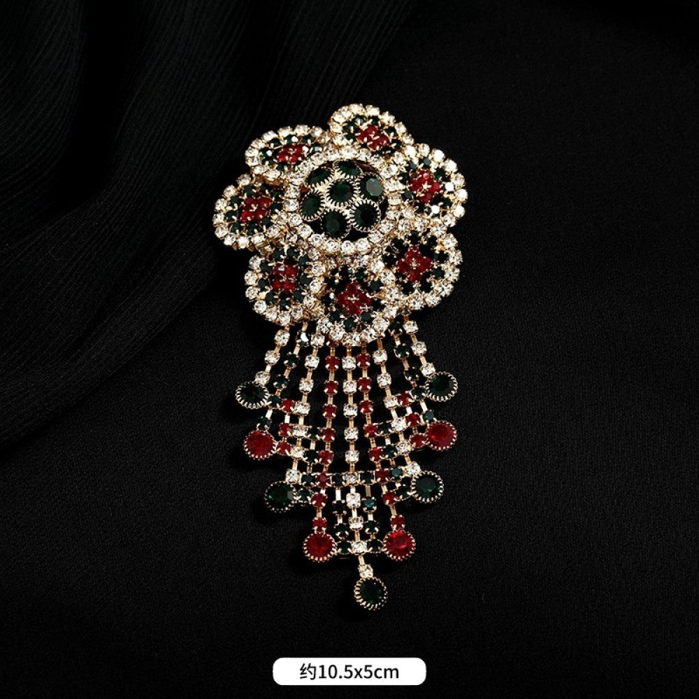 This ornate multi-layer floral brooch features vibrant red and green gemstones set in a clear crystal frame, adding a touch of vintage glamour to any outfit. Measures approx. 5x5cm 03