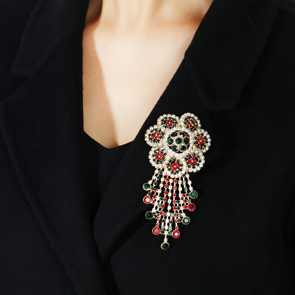 This ornate multi-layer floral brooch features vibrant red and green gemstones set in a clear crystal frame, adding a touch of vintage glamour to any outfit. Measures approx. 5x5cm 06