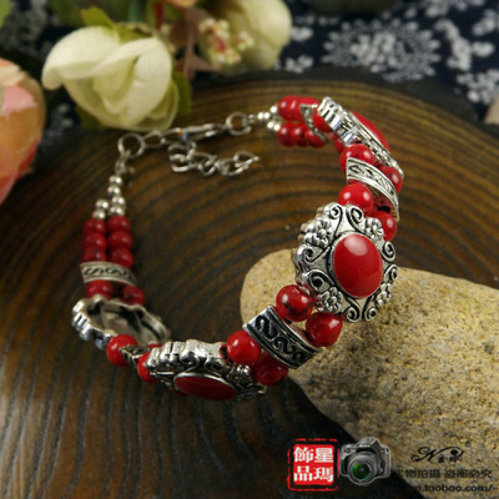 This ethnic-style bracelet features vivid red beads paired with ornate silver-tone filigree details and an adjustable clasp, delivering a bold retro look for daily wear