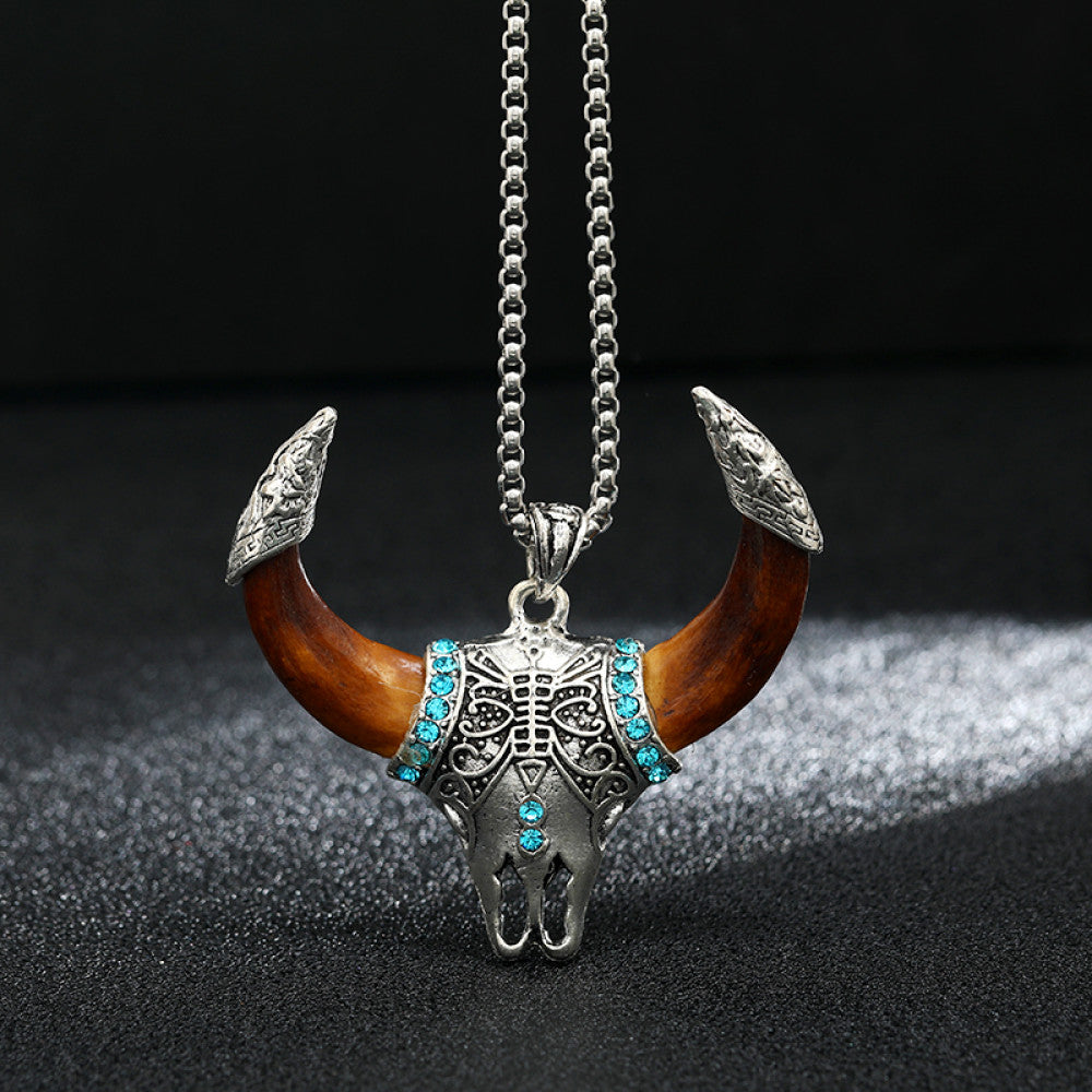 Vintage silver-toned bull horn skull pendant necklace with turquoise accents, intricate metal carvings, and brown horn details, paired with a silver ball chain, perfect for Western boho style, showcased against a black textured background