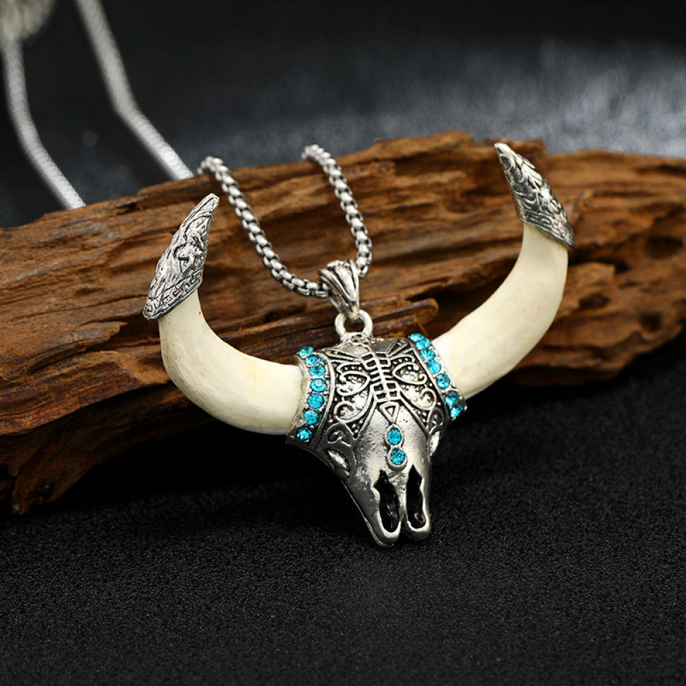 Vintage silver-toned bull horn skull pendant necklace with turquoise accents and intricate carvings, paired with a silver chain, perfect for Western boho fashion, showcased against a black textured background
