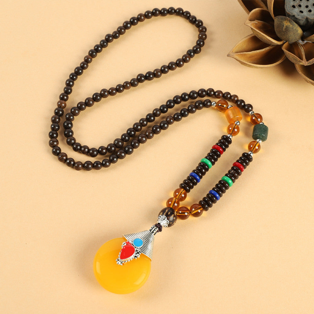 Vintage bohemian ethnic beaded necklace with red pendant and multi-color beads, ideal for spiritual boho fashion, displayed with a decorative flower against a neutral background 01