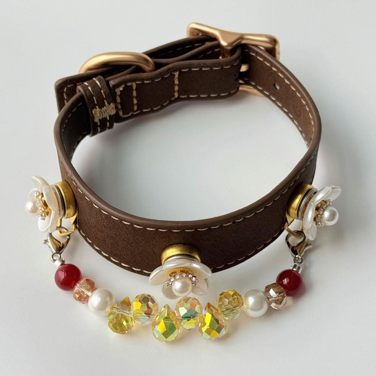 Overhead curved studio shot of brown leather pet collar with flower and multi-color bead chain | DIY Jade