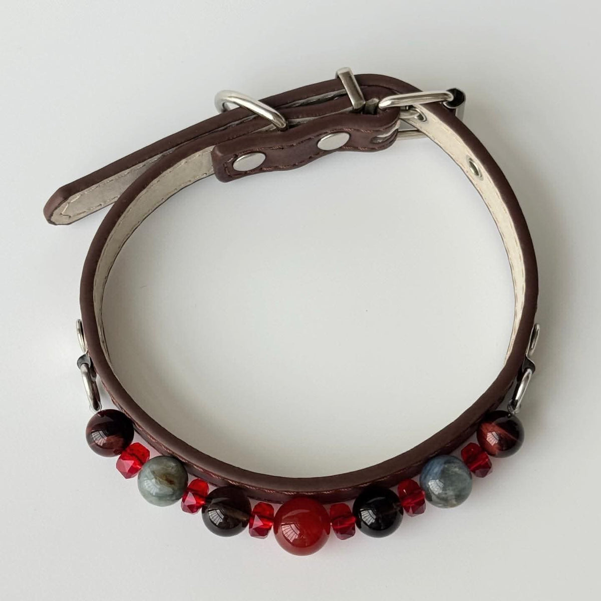 Overhead curved view of brown pet collar with red and dark gem bead accents | DIY Jade
