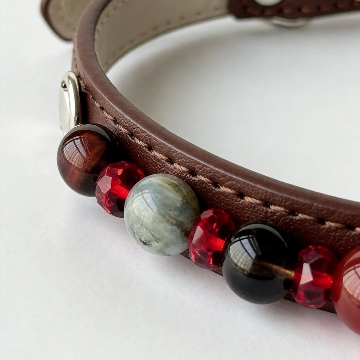 Macro closeup of brown pet collar showing red, black and grey gem bead details | DIY Jade