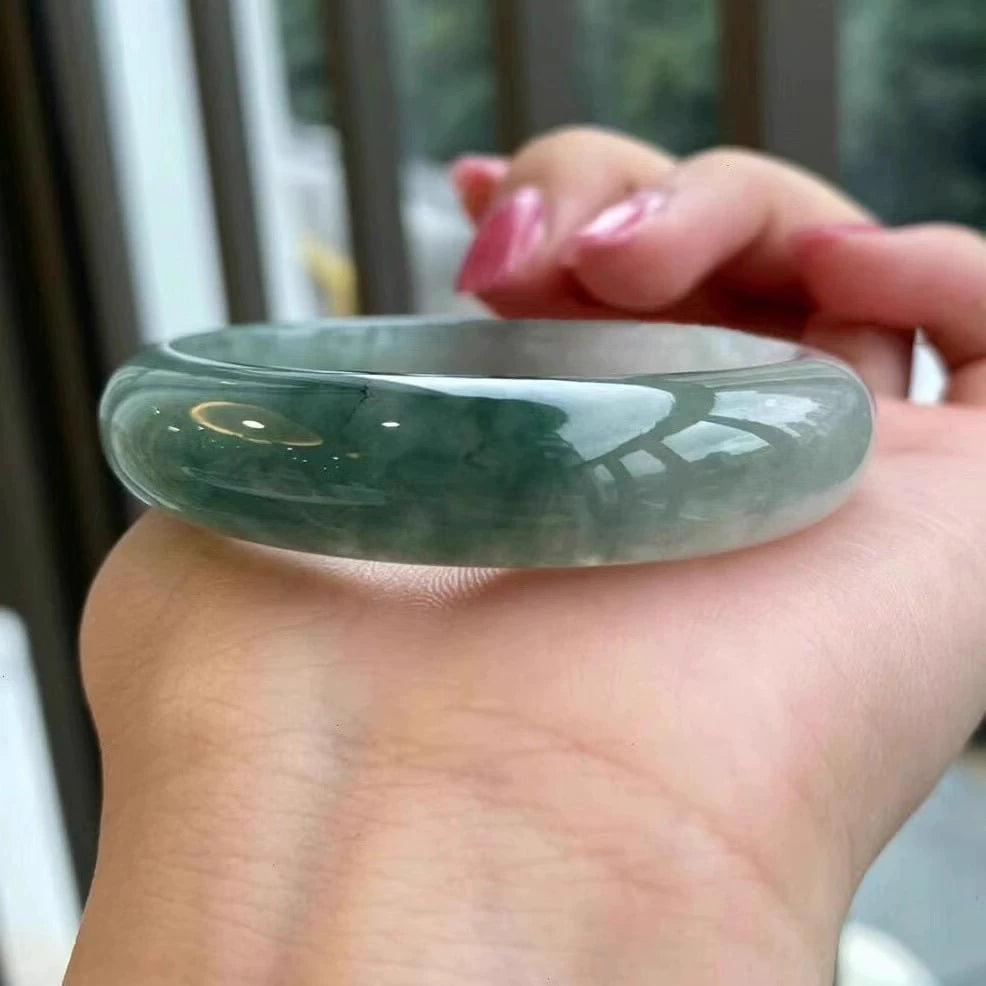 Natural dark green floating flower jadeite bangle bracelet, held in hand to show glossy surface and natural patterns | DIY Jade
