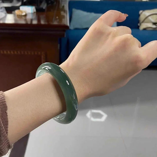 Natural dark oil green jadeite bangle bracelet worn indoors, showing rich color and glossy finish | DIY Jade
