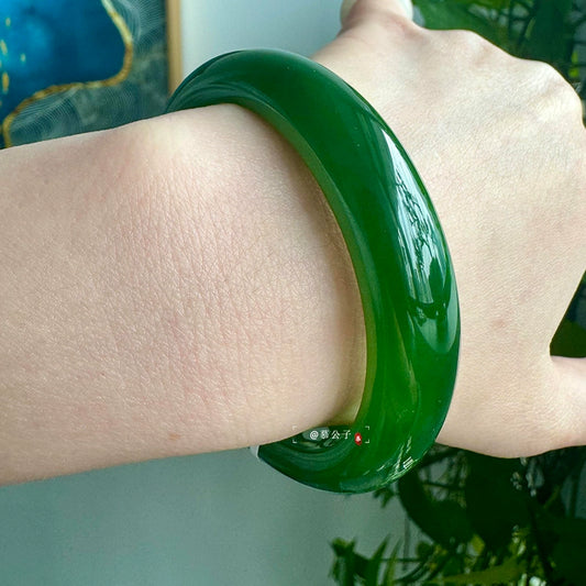 Deep green jade bangle side view worn on wrist, showing glossy surface texture | DIY Jade