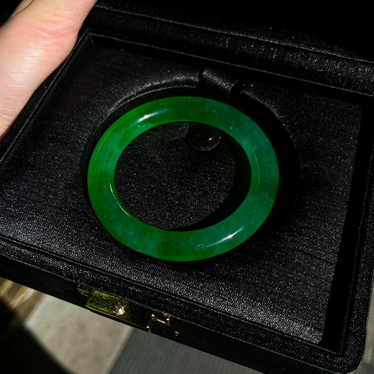Emerald green jade bangle displayed in black jewelry box, showing rich color and glossy finish | DIY Jade
